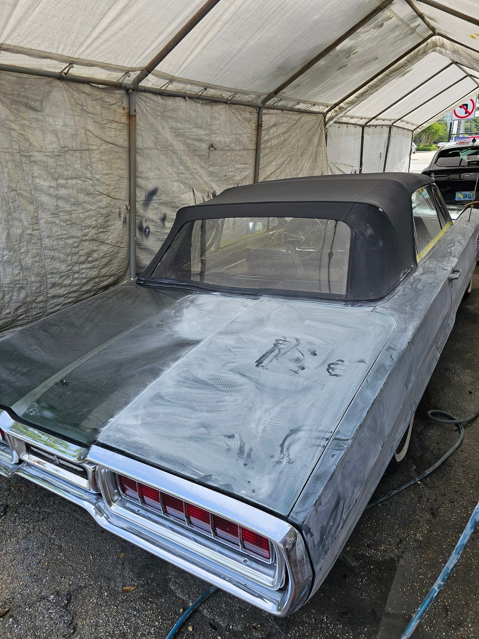 Classic convertible with primer on the trunk and rear deck in a covered work area